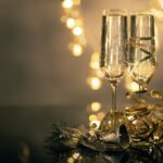 Close-Up Of Two Flute Glasses Filled With Sparkling Wine Wuth Ribbons And Christmas Decor